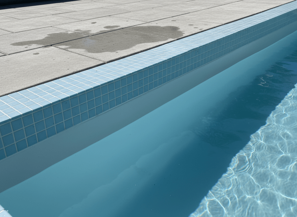 Revestimiento de azulejo azul claro recién aplicado en el borde de una piscina